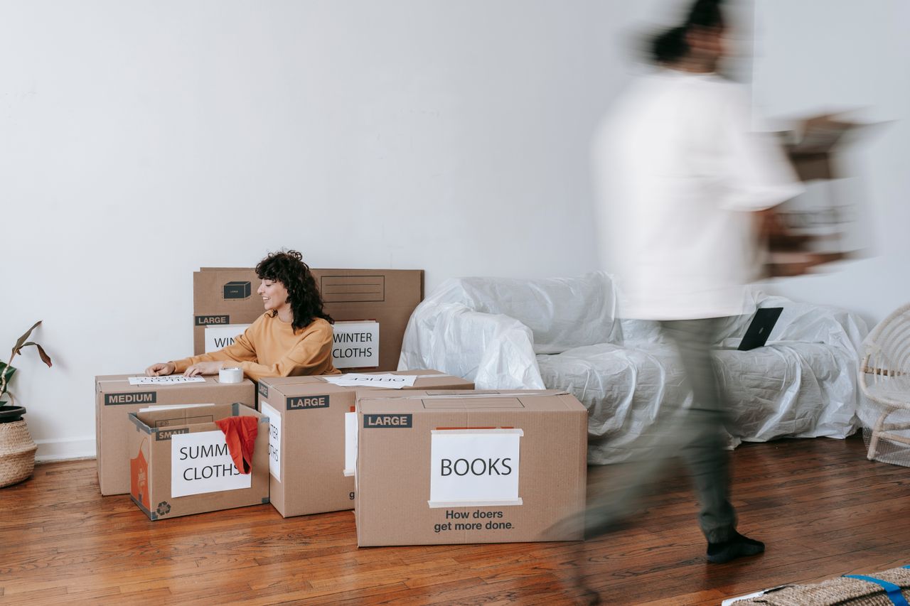 Un couple range des cartons étiquetés dans un salon minimaliste, en train de préparer le jour du déménagement.