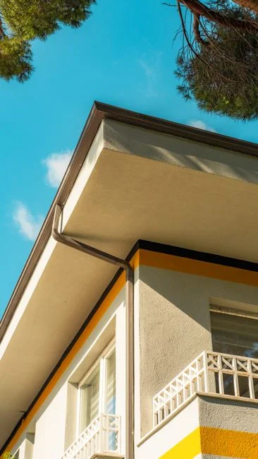 Canapé recouvert d’un drap et lampe sur pied, avec des cartons emballés dans une pièce lumineuse et spacieuse d’une maison contemporaine neuve